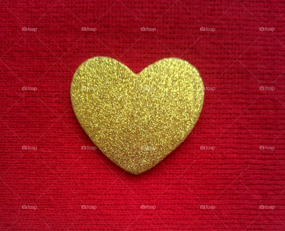 Gold coloured heart shape against red background