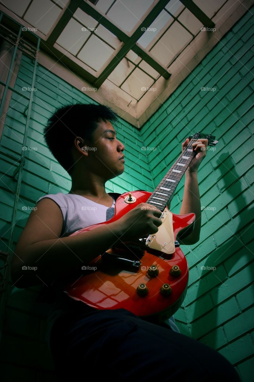 young asian teenager playing an electric guitar