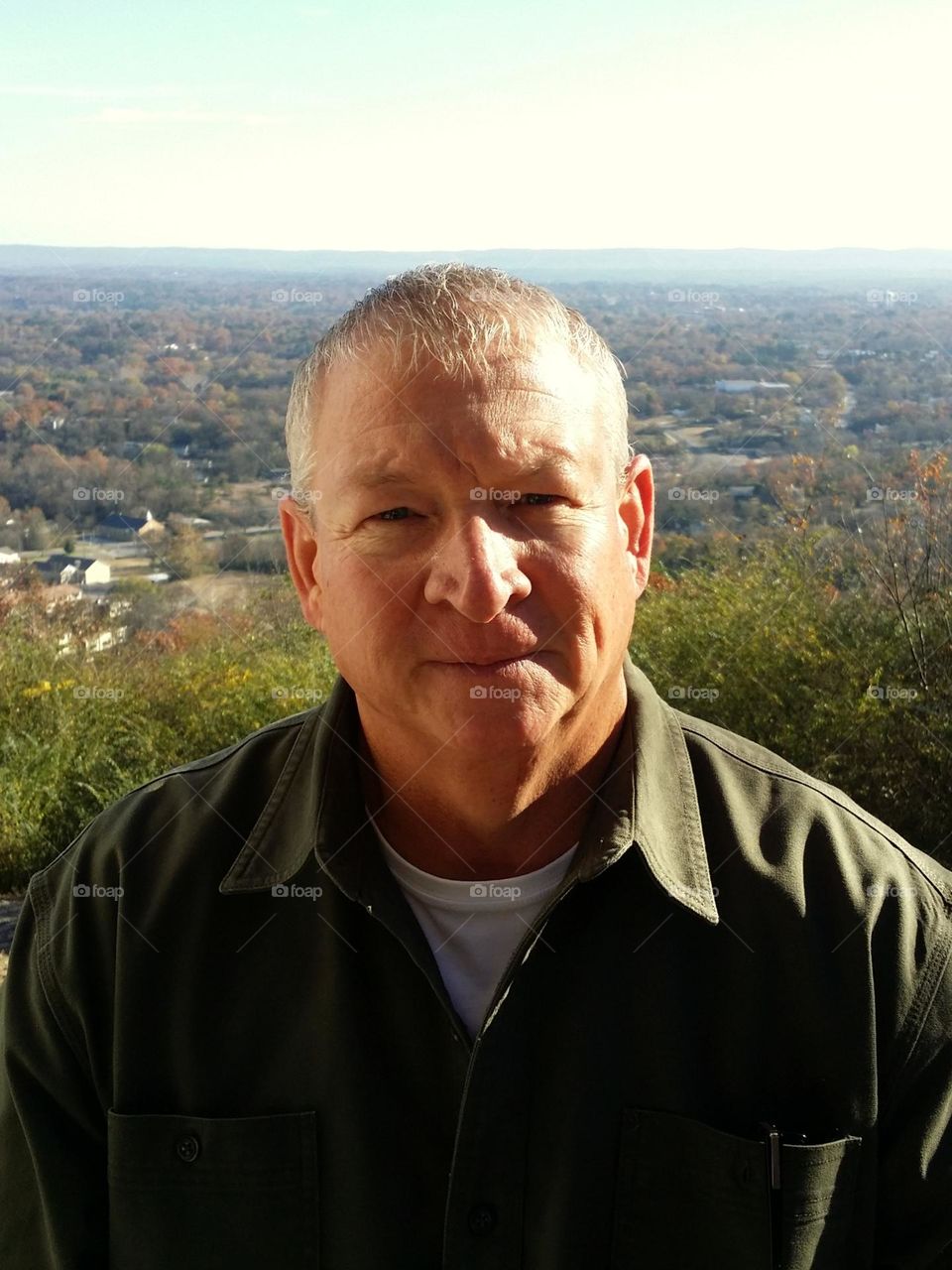 A clean shaven man sitting in front of Hot Springs Arkansas fall leaves in the background