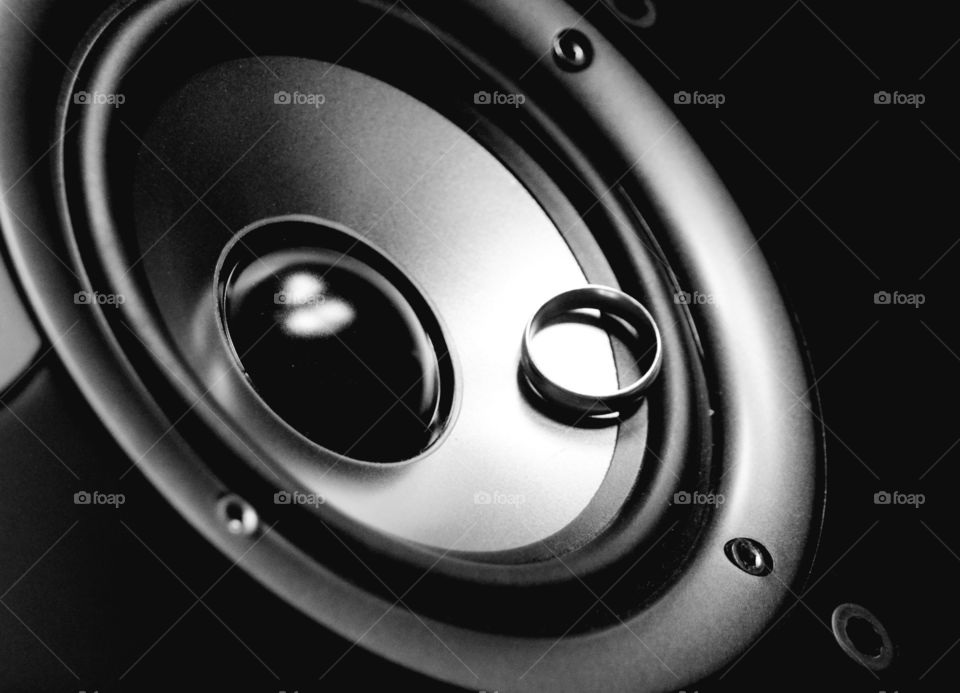A black and white of a ring spinning along its axis on the inner rim of a rotating stereo speaker.