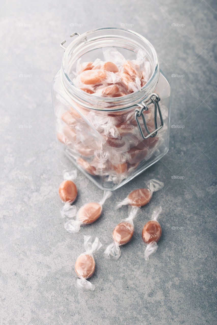 Jar filled with caramel milky candies on table