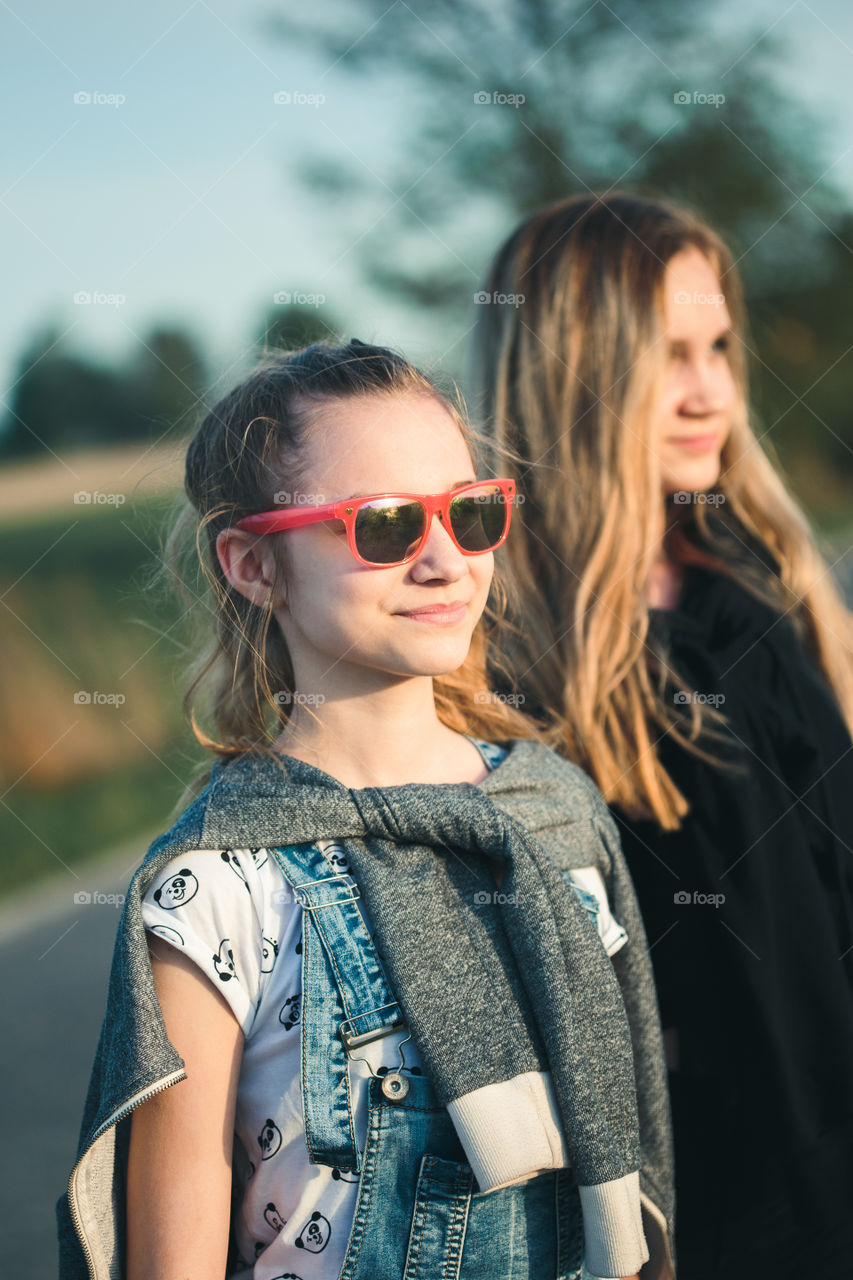 Teenage smiling happy girls having fun walking outdoors, hanging, spending time together on summer day. Real people, authentic situations