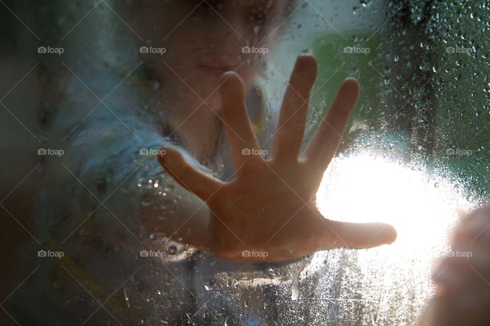 sad portrait of a boy through wet glass