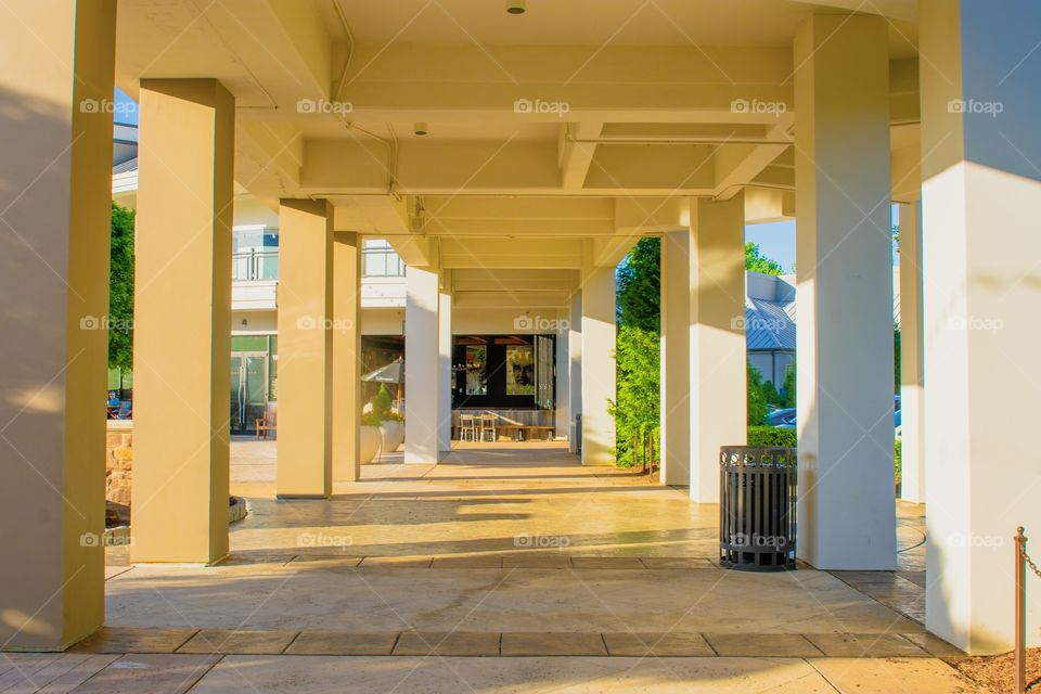  Columned white outdoor structure at shopping mall on beautiful spring day.