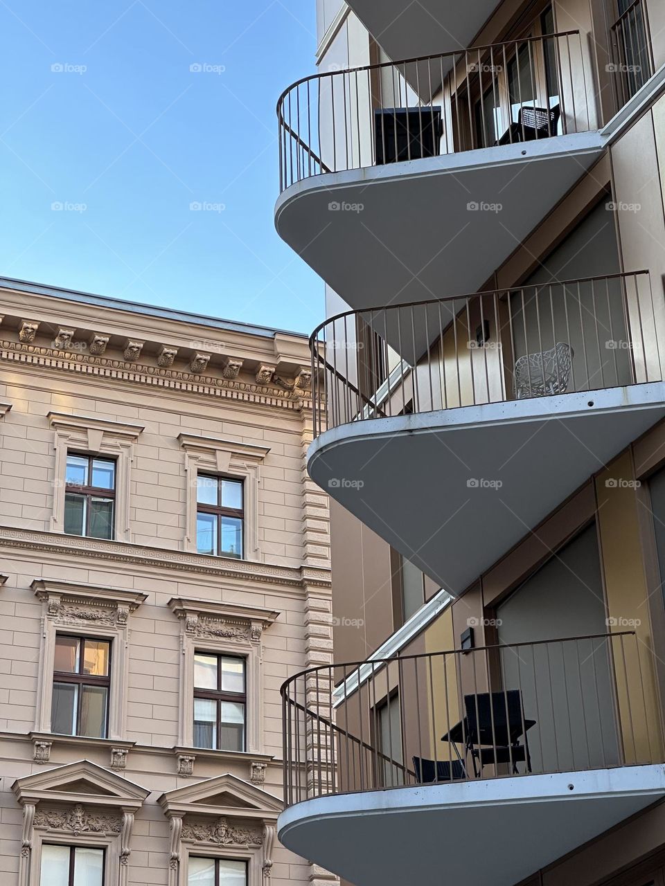 Modern building with triangle balconies against a background of a classical old building. 