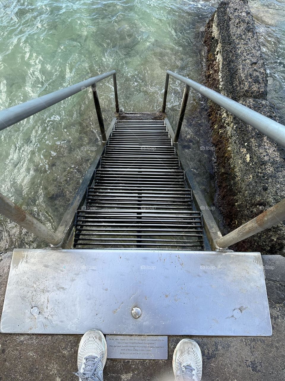 Self portrait featuring my feet in running shoes taking a picture looking down a steel staircase providing entrance to the ocean