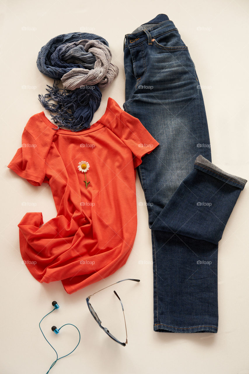 An orange t-shirt and jeans with the accessories 