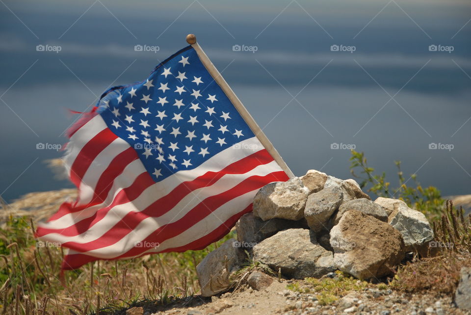 A close up view of a American flag blowing in the wind with the background of the sky!