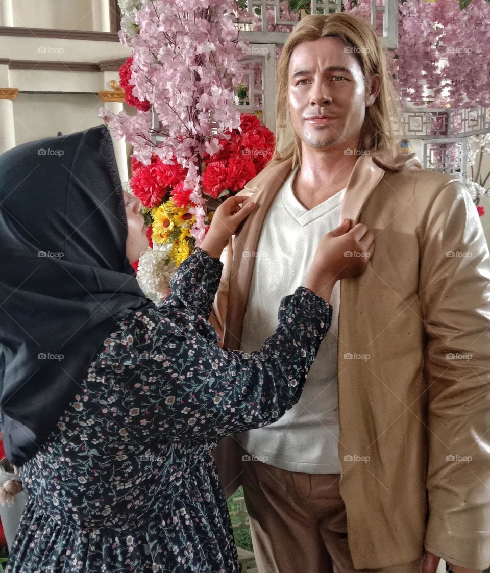 A woman is taking a cute photo with a wax statue at a tourist spot.