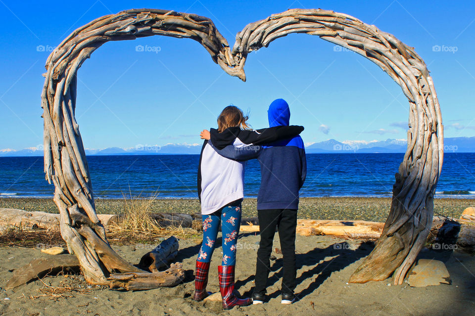 These two kids have grown up together on our island & they appreciate so much the beauty of Nature & all it’s gifts. Here they are under a driftwood heart staring out appreciatively at the ocean & the mountains at sunset on a beautiful February day.