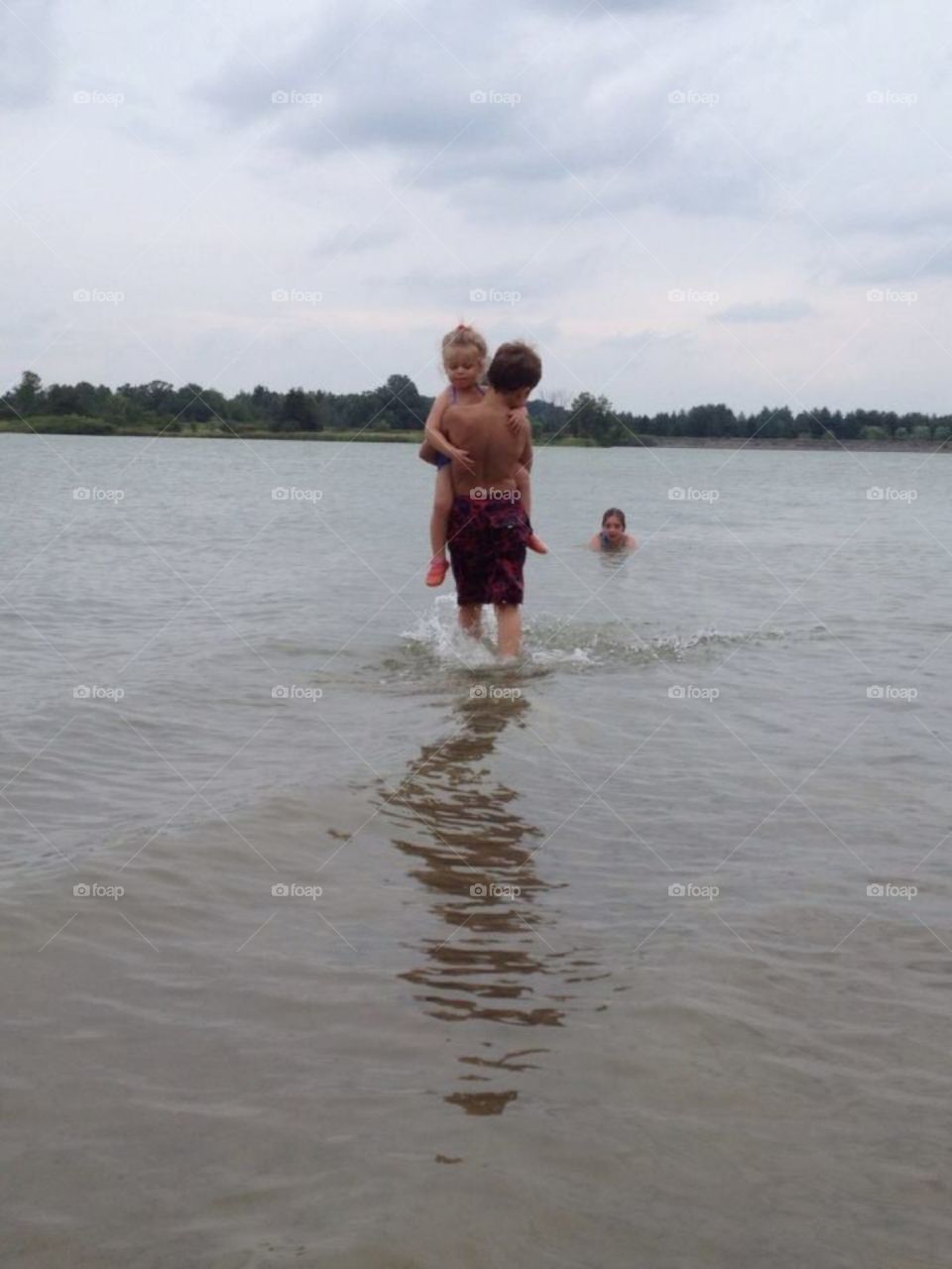 Brother carrying sister into water