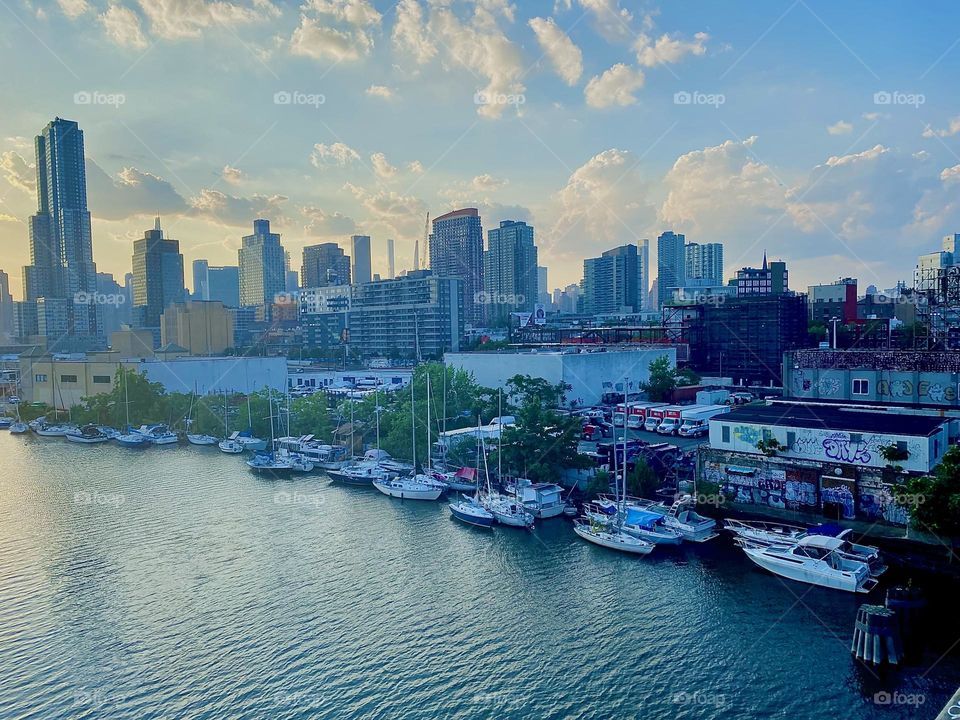 This is the view of “Newtown Creek” with its variety of boats seen from the top of the “Pulaski Bridge” just before twilight time at dusk. 2023. Hypnotic Productions