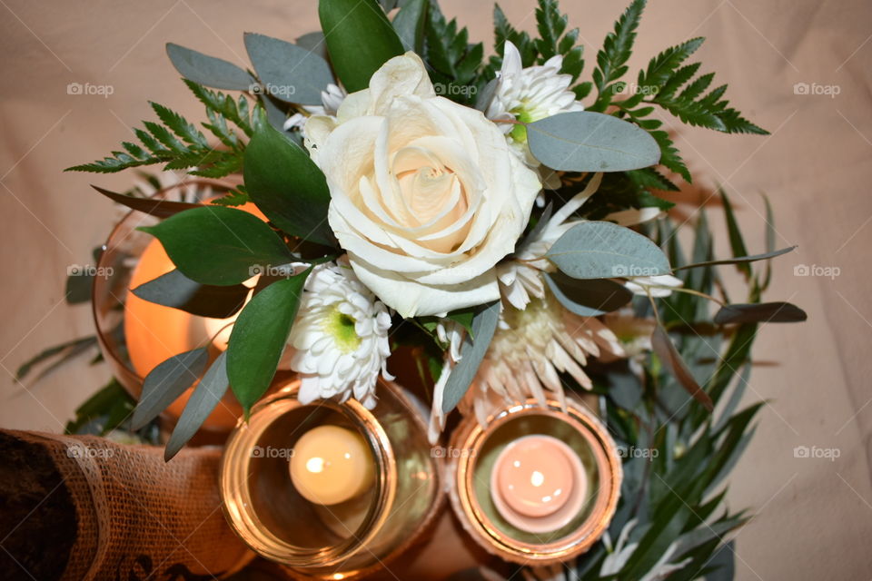 A small bouquet completes a centre piece with a willow and eucalyptus wreath at the base surrounding a live edge wood slab. Candles and a table number made of a log and burlap tie it together. 