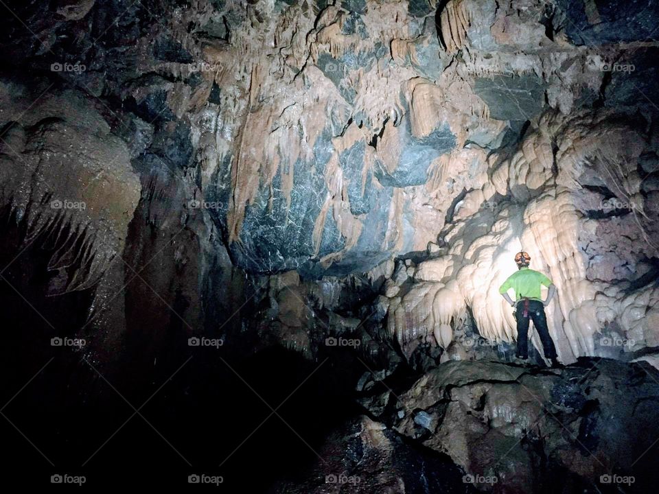Hiking deep in the Vietnamese cave systems of Phong Na National Park with a cave guide shining his light on the roof covered with stalagmites