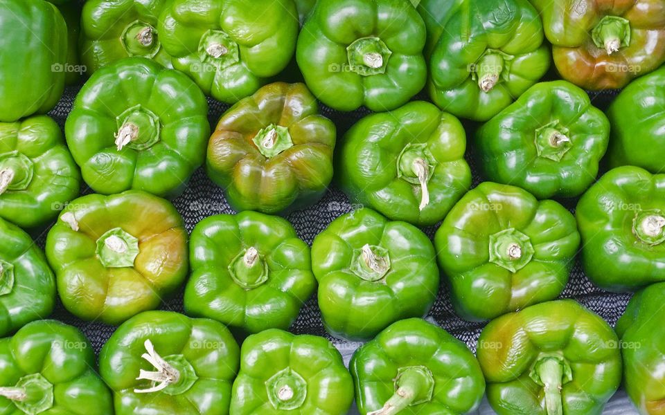 Many raw green peppers outside a grocery store in New York City
