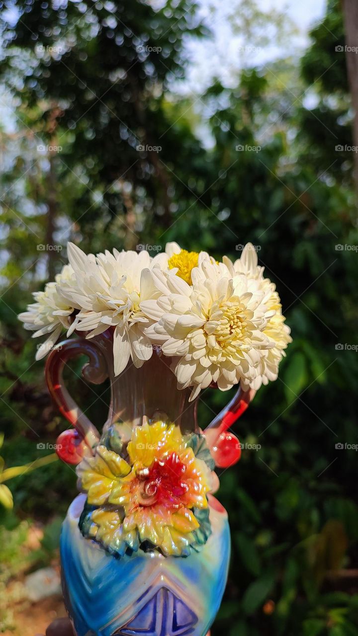 Beautiful white flowers in a colourful flowerpot with a flower sculpture, Flowers in a vase, colourful vase, white flowers in a vase