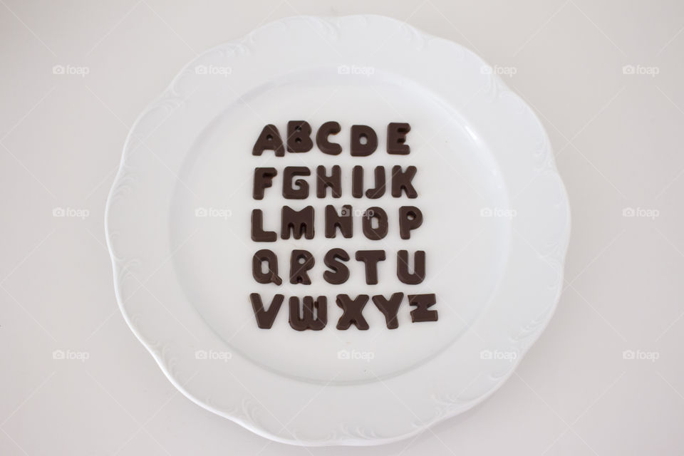Alphabet chocolate letters on white plate 