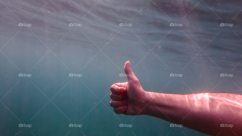 thumbs up underwater in the deep blue sea