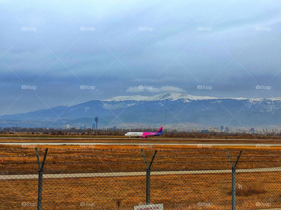 A beautiful scenery by the airport in Sofia, Bulgaria with an airplane in the centre and the beautiful Vitosha mountain covered in snow in the back