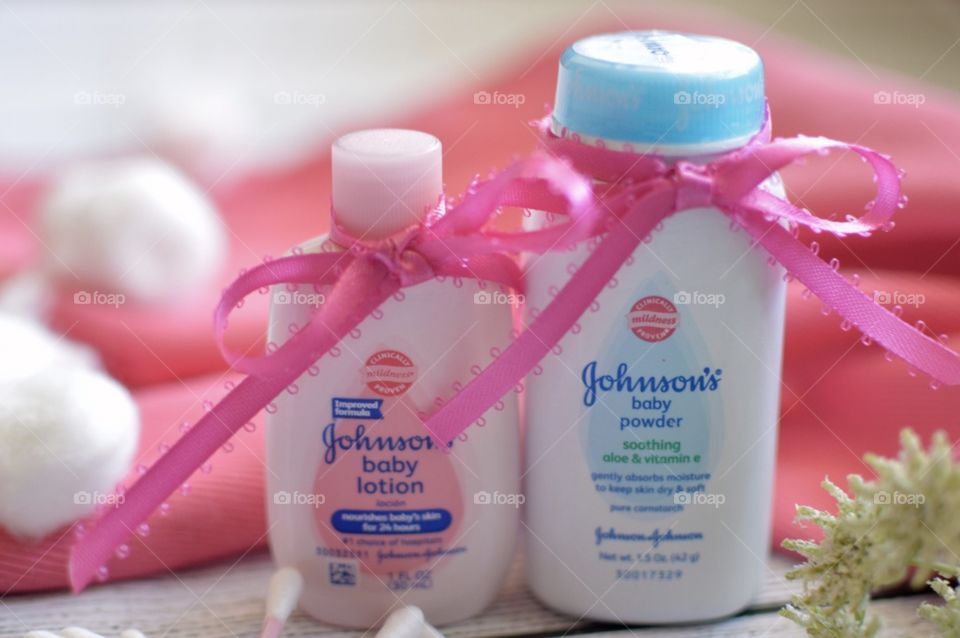 Johnson and Johnson baby lotion and powder with a pink ribbon and white background