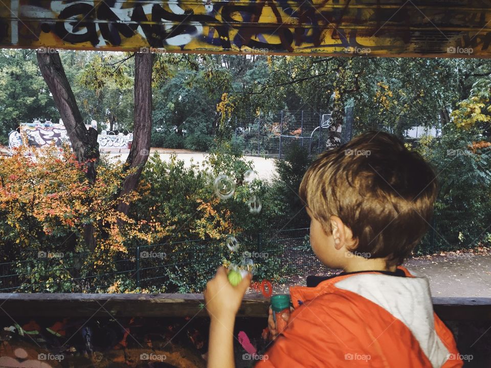 Soap bubbles on playground. Boy blowing soap bubbles from a playground house