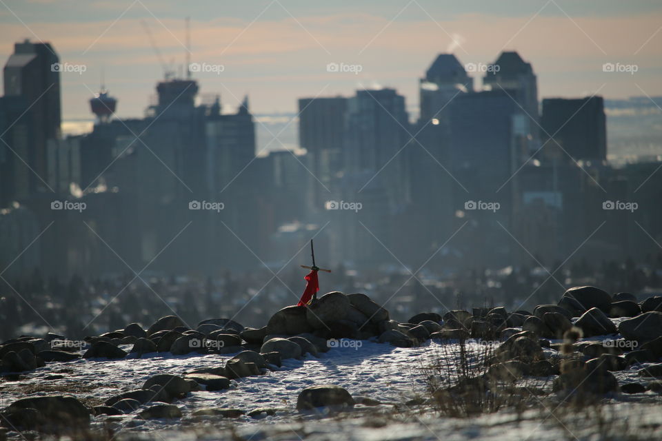 downtown Calgary behind a medicine wheel with a cross and red flag in the center