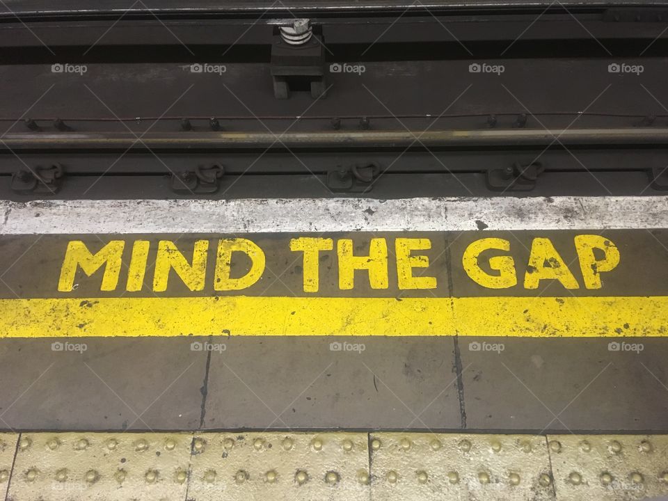 MIND THE GAP painted in yellow at Borough Station, London. At the far end of the northbound Northern Line platform. Captured during the evening rush hour in Summer