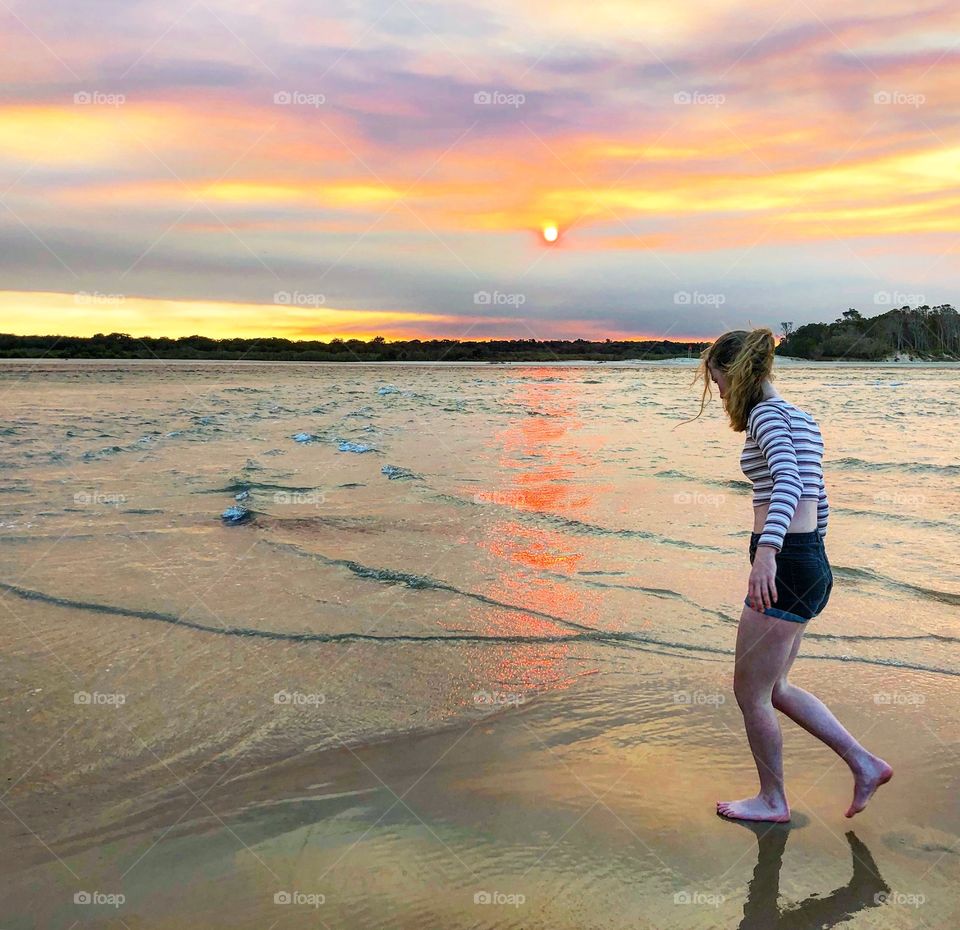 Walking in the wet sand at sunset under a blazing sky