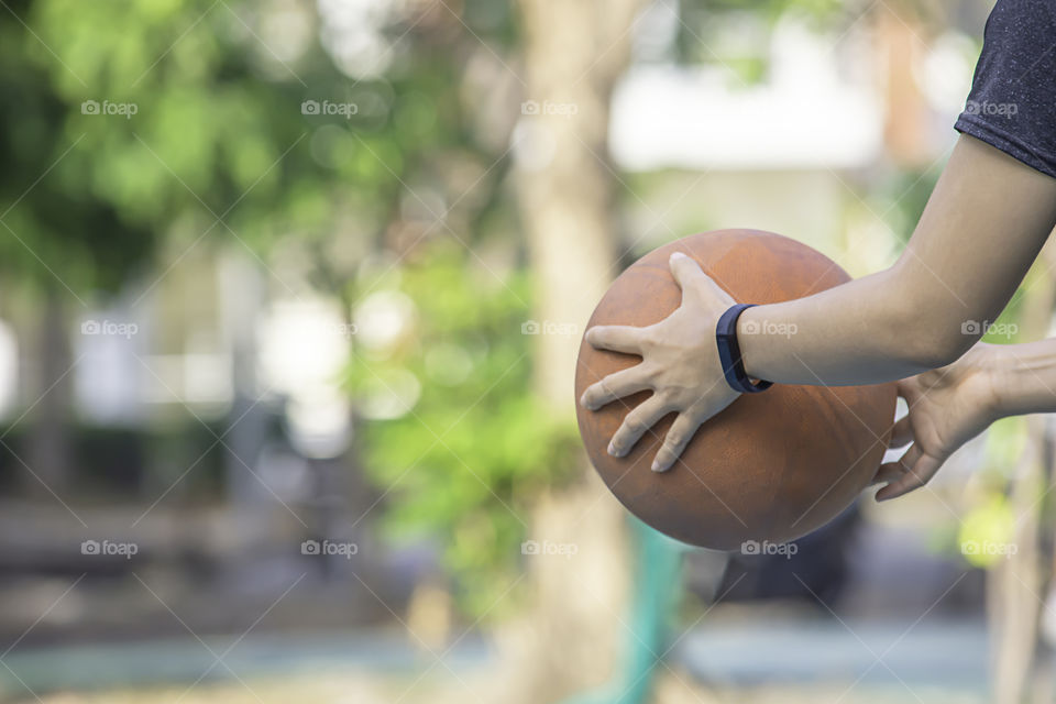 Hand of a woman wearing a watch And holding old basketball .