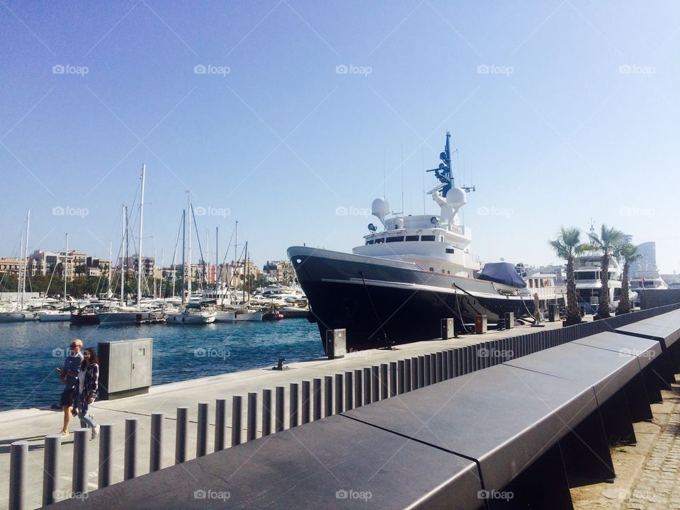 Super yacht moored at beautiful Port Vell in Barcelona Spain on a sunny Autumn day against a blue sky 