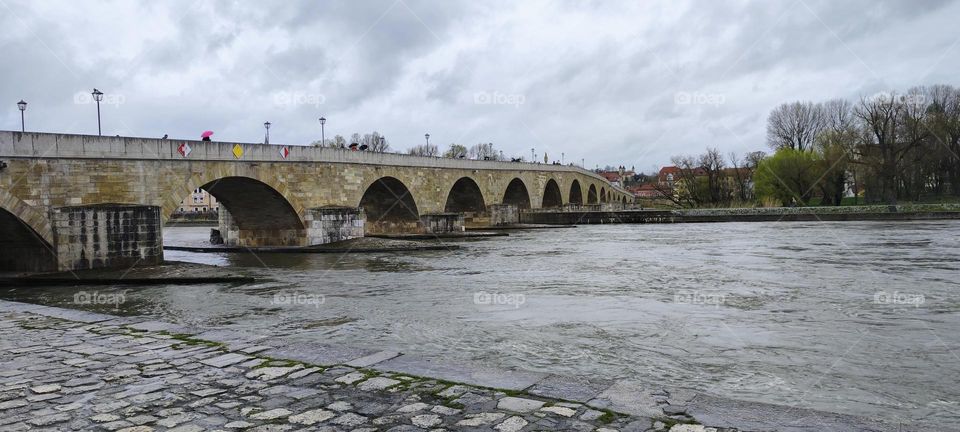 The river “Danube” frequently rises to very elevated levels as can be seen in this picture taken in the city of “Regensburg”. The antique bridge is known as the “Steinerne Brücke” or the “Stony Bridge”. 2023. Hypnotic Productions