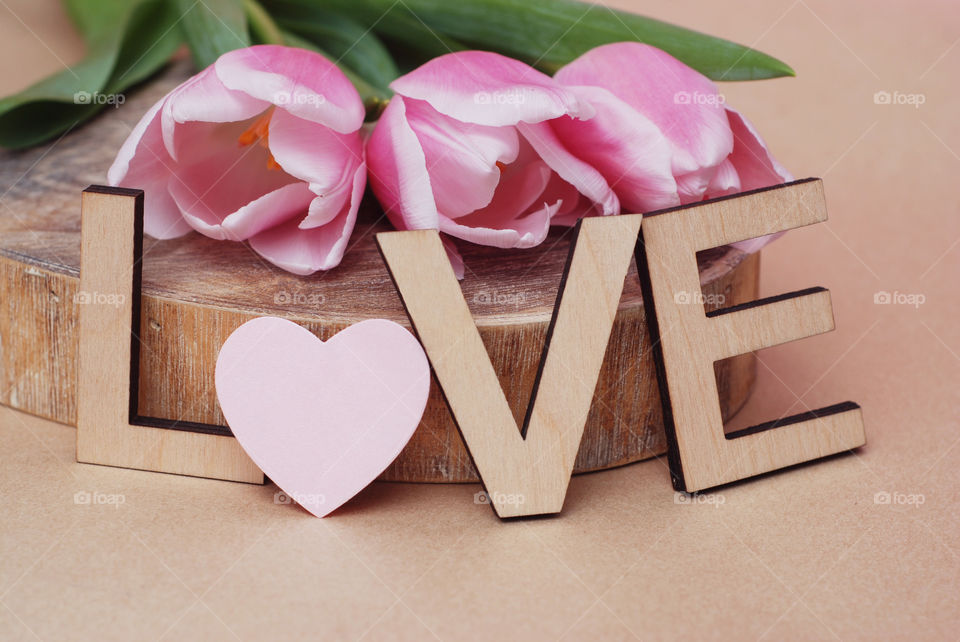 Beautiful pink tulips and wooden letters "Love" inscription.