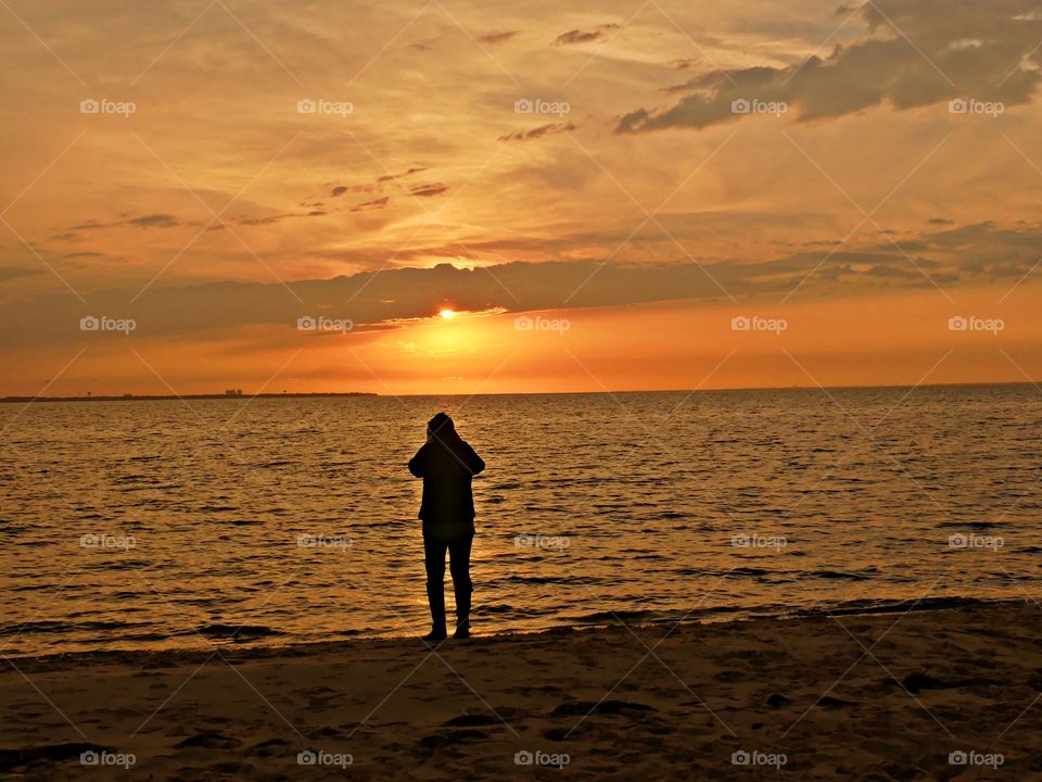 A young lady capture a colorful and majestic sunset. The awesome beauty of the setting sun is also symbolic of the beauty and mystery of life itself