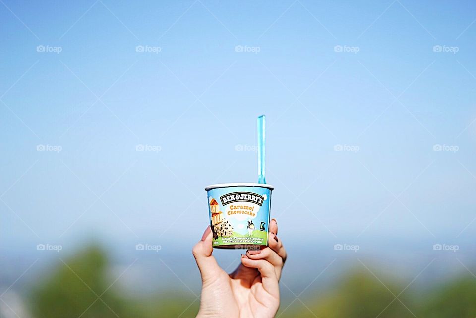 Brisbane, Australia - April 15, 2018 : A photo of hand holding Ben and Jerry’s ice cream, caramel cheesecake flavor. Holding ice cream cup up in the air. Shallow depth of field. Editorial use only