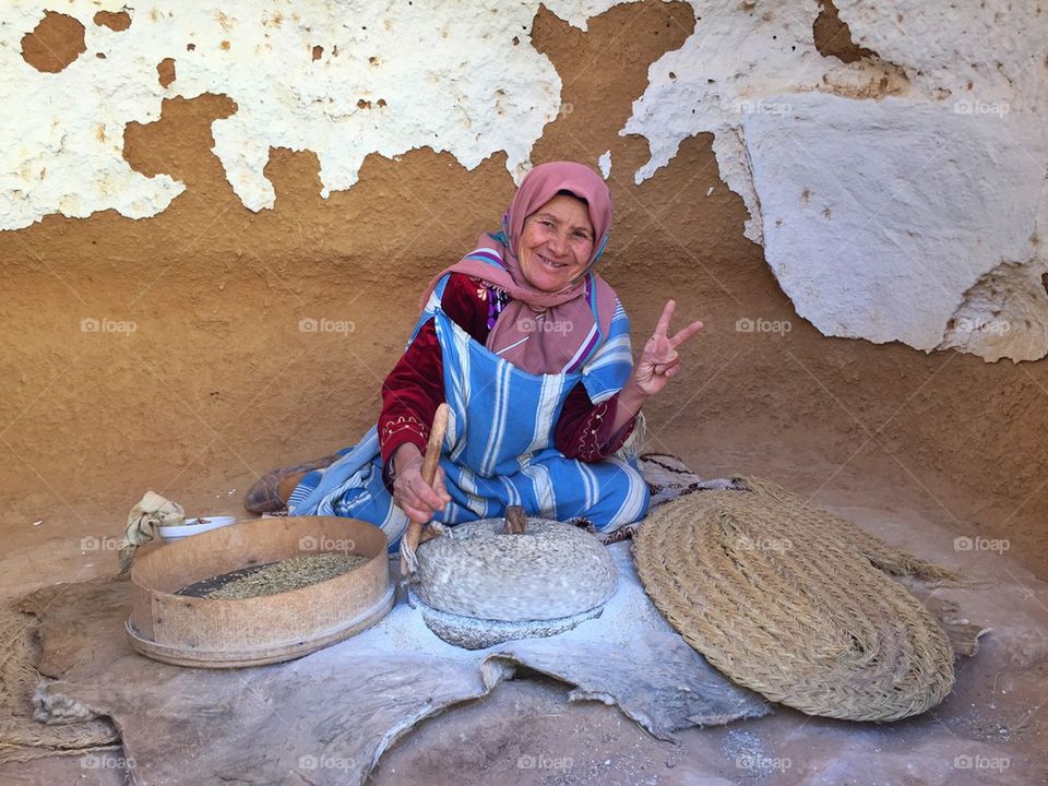 Senior Berberian woman smiling whilst grinding wheat to make floor in the Tunisian desert 