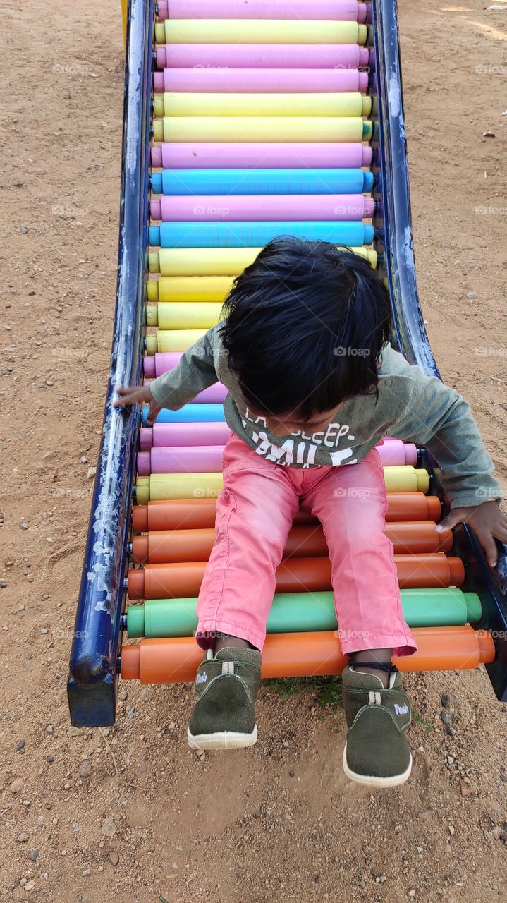 Play time - kid playing on vibrant rainbow colours slide