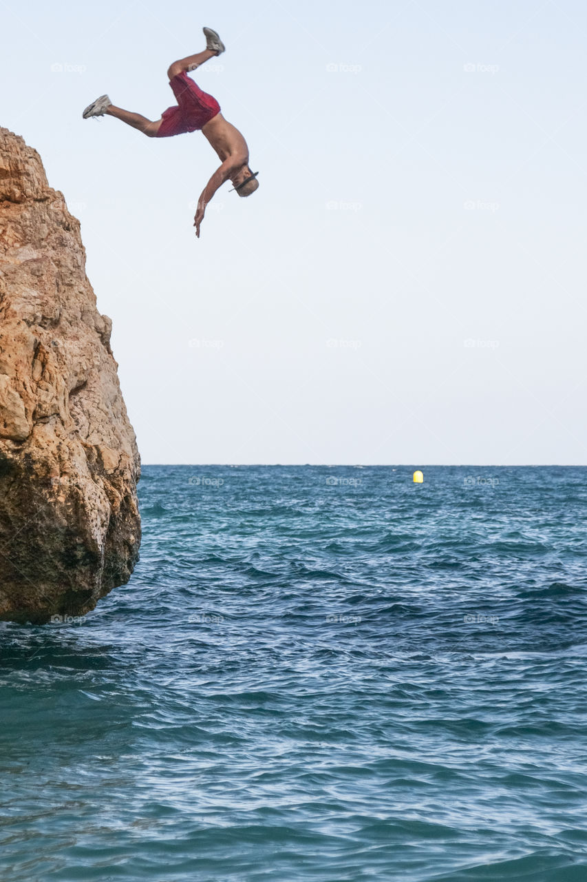 Man jumping into the sea from a cliff. Summer vacation 