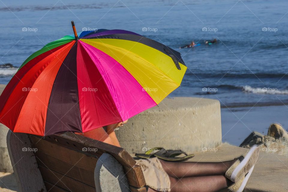 relaxing on a beautiful summer day in Capitola california at the beach. on a bench using a colorful umbrella to shield from the sun