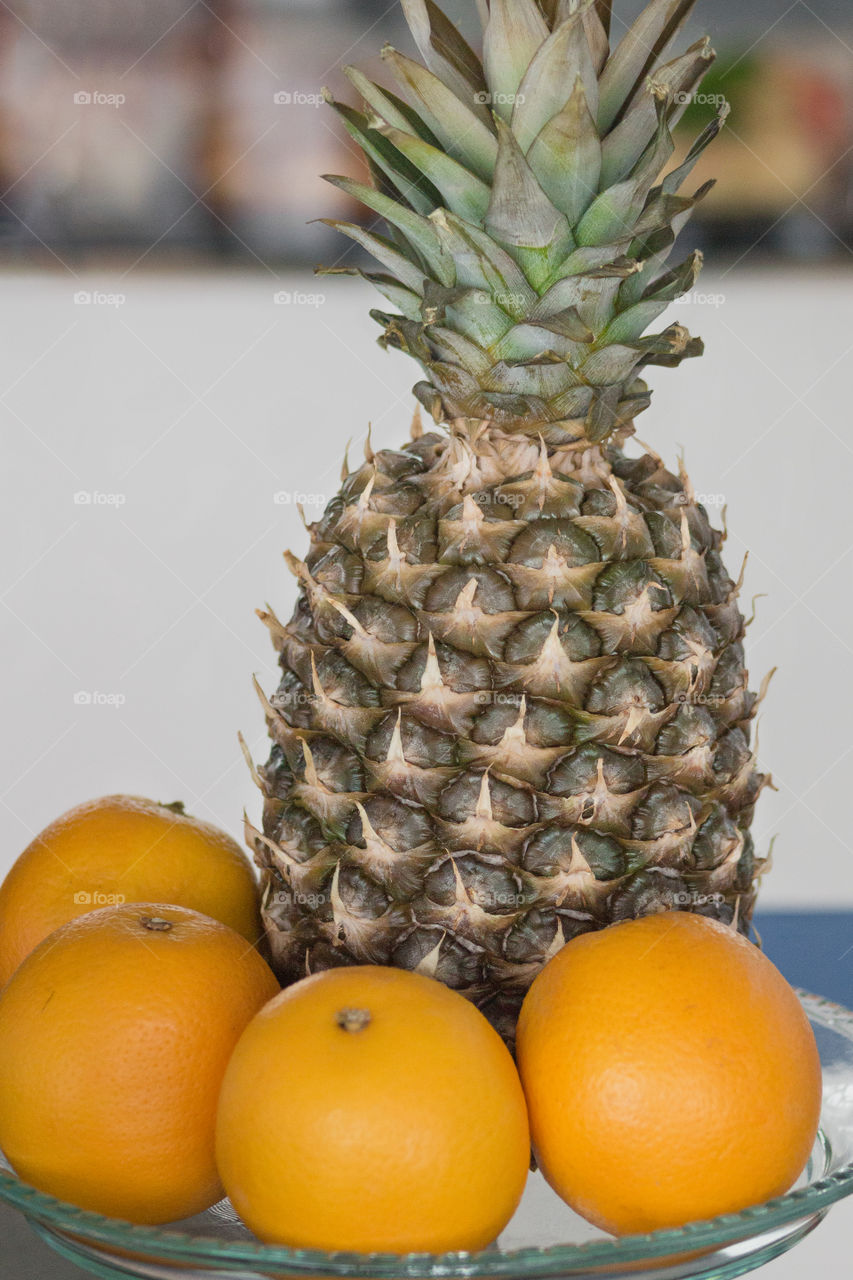 Pineapple and oranges lie on a glass dish