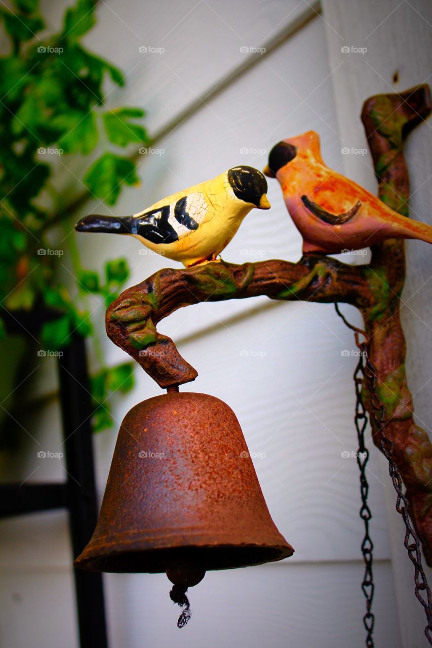 Rustic dinner bell with birds on a back porch.