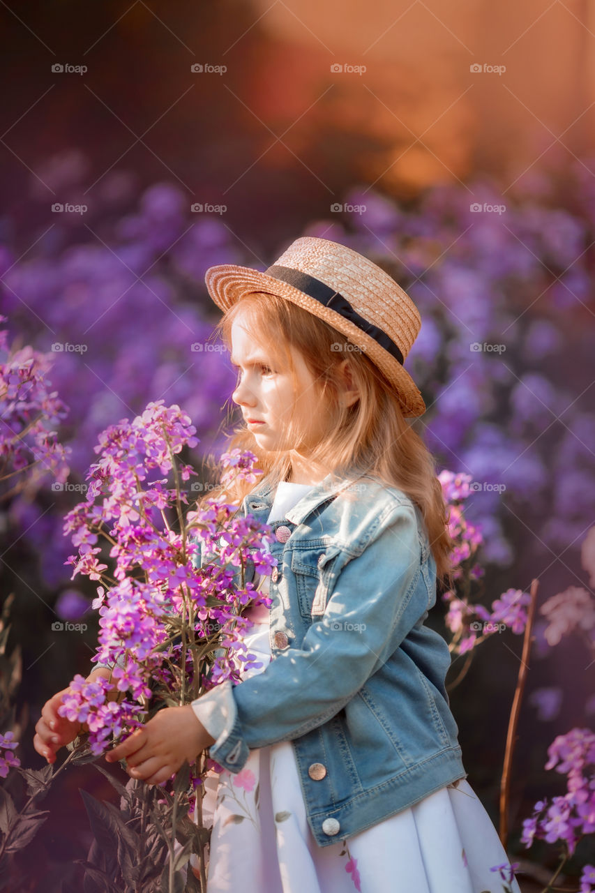 Cute little girl portrait in blossom meadow at sunset 