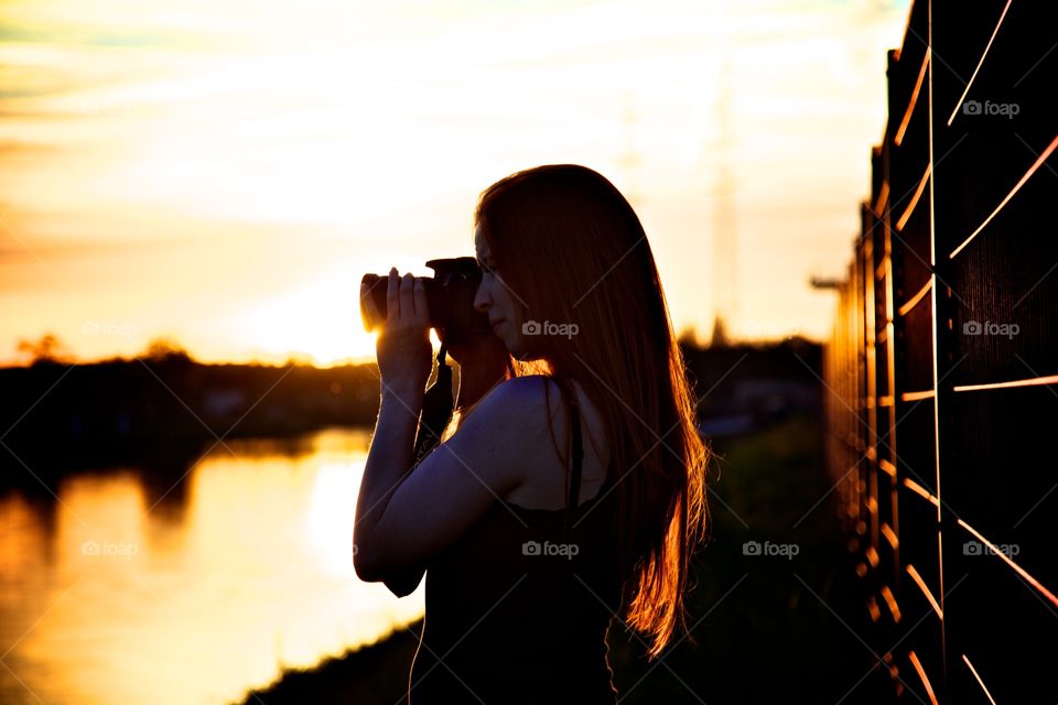 a redhair woman makes photo from the sundown in the port from karlsruhe