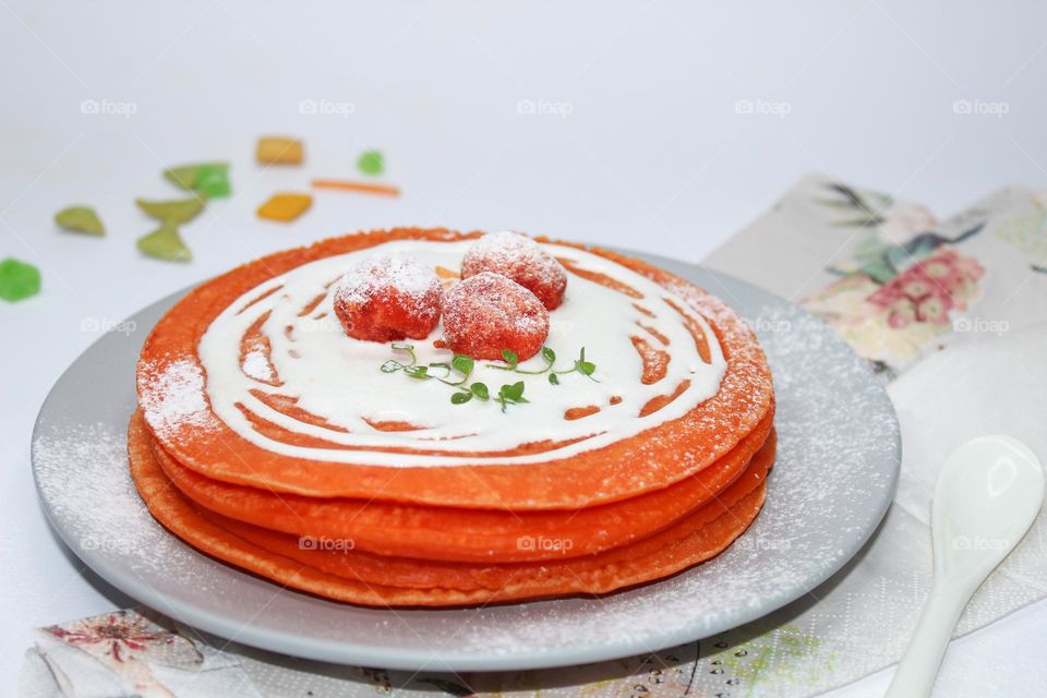 Orange pancakes with sour cream and candied fruit on a gray plate.  Excellent breakfast