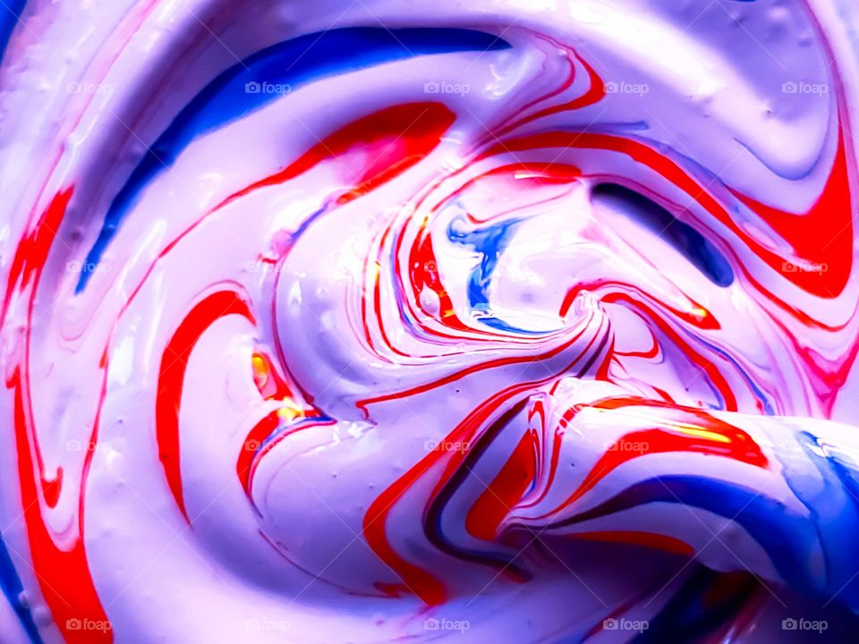 Creating purple with acrylic paint. Closeup of the mixing of white, red and blue acrylic paints.