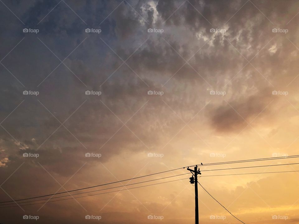 Power lines on dramatic sky at sunset