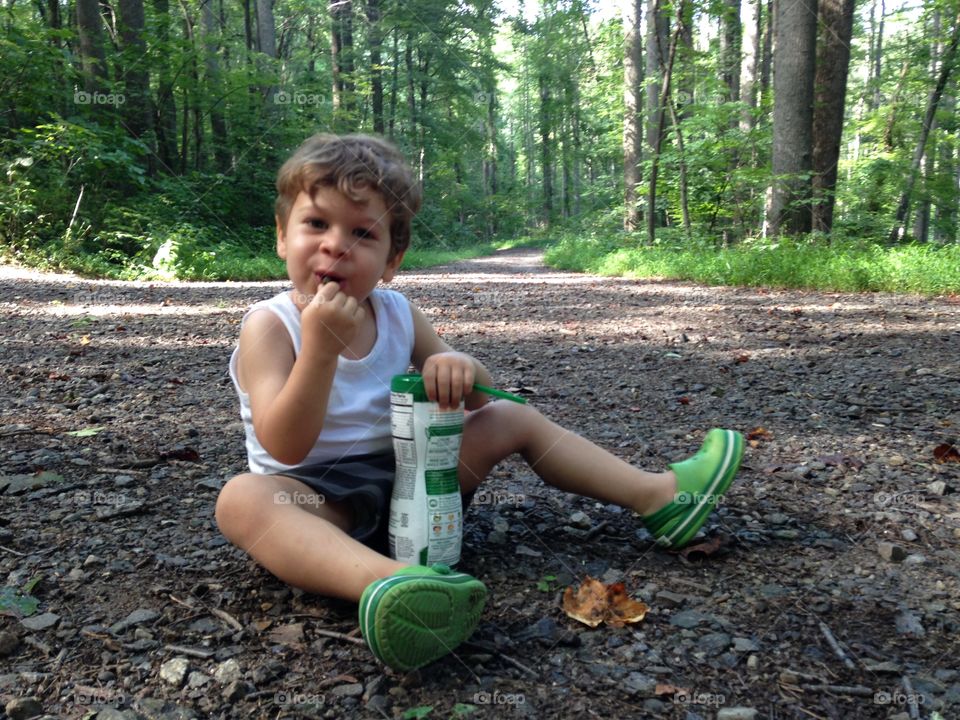 Boy having a snack sitting in the woods.