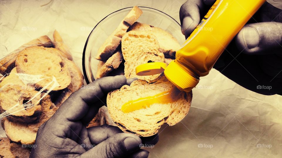 Preparando fatias de pão seco, com mostarda.