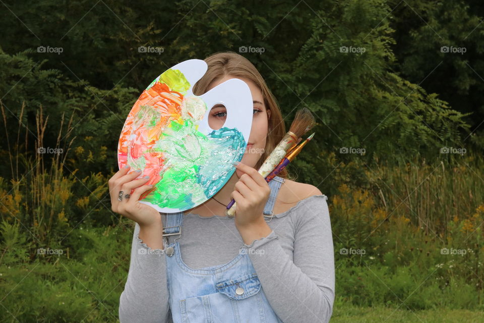 Young artist senior year photo shoot. Holding colorful pallet. 