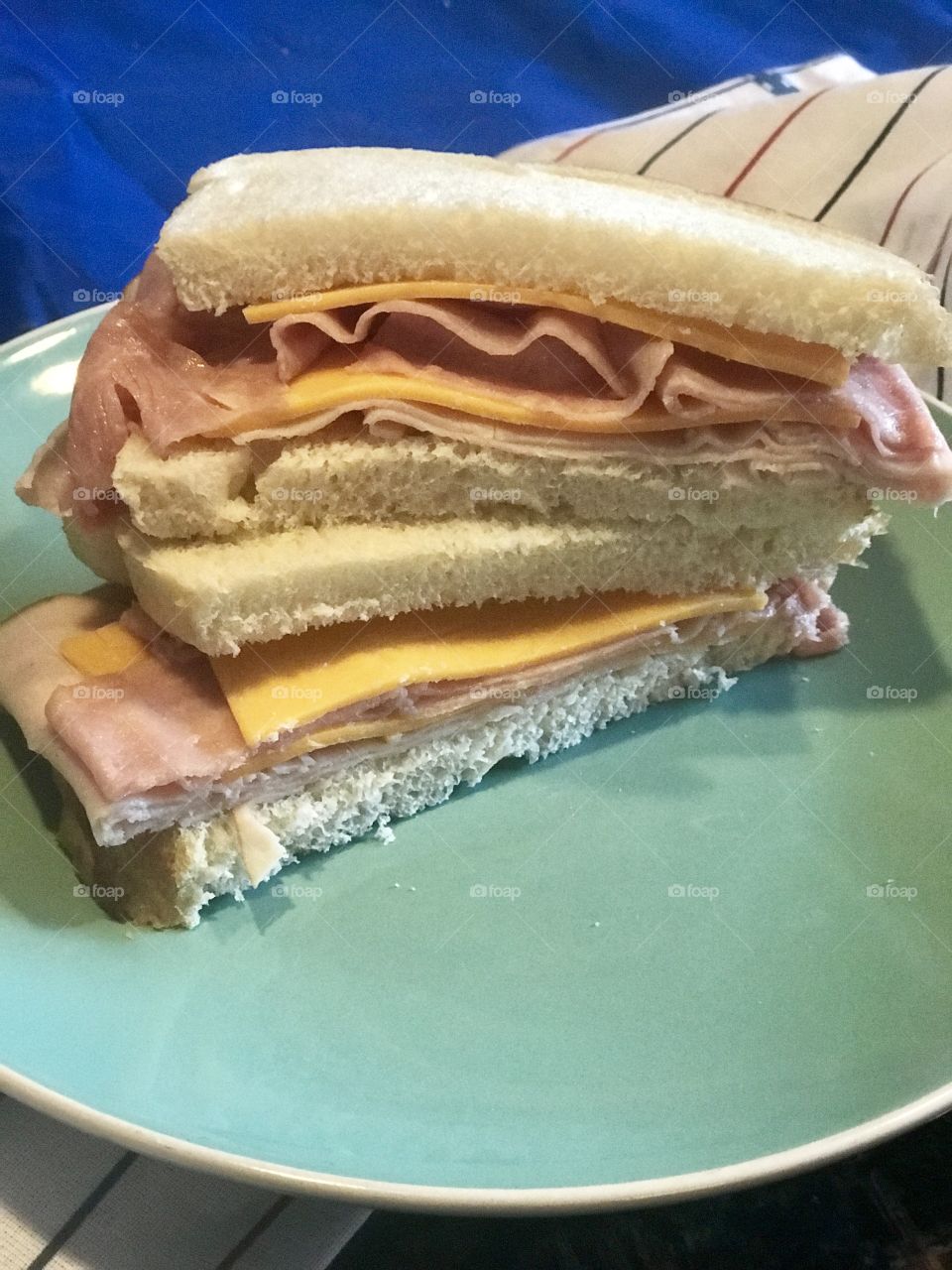 A delicious ham and cheddar cheese sandwich served on white bread on a plate and a striped napkin. USA, America 