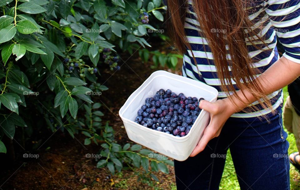 A woman holding blueberries in container
